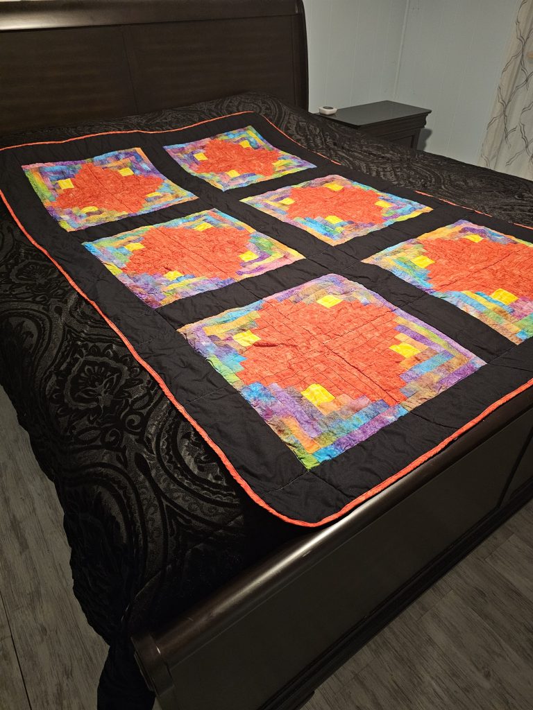 Log Cabin Batik Red Diamond Quilt pictured on bed