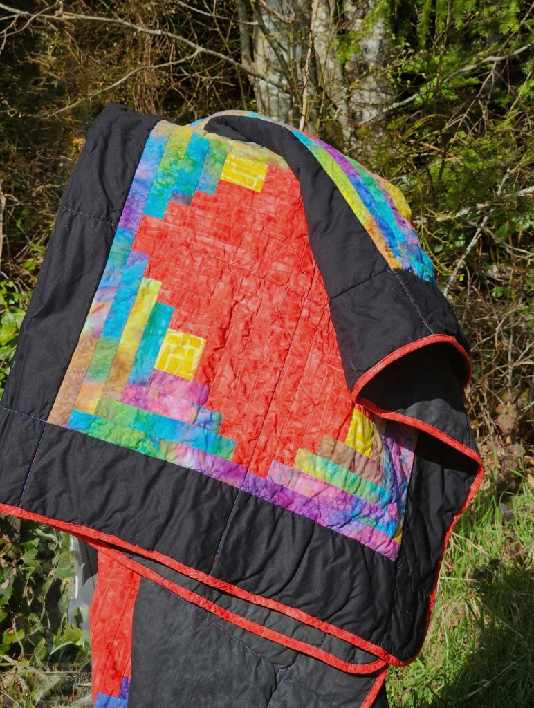 Log Cabin Batik Red Diamond Quilt held by hand